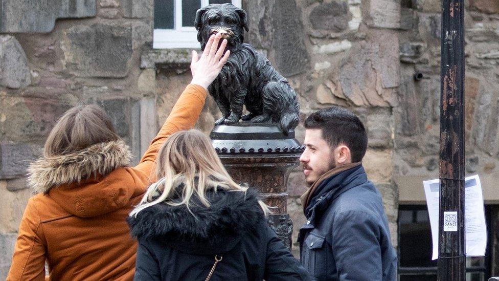 tourists touch Bobby's nose