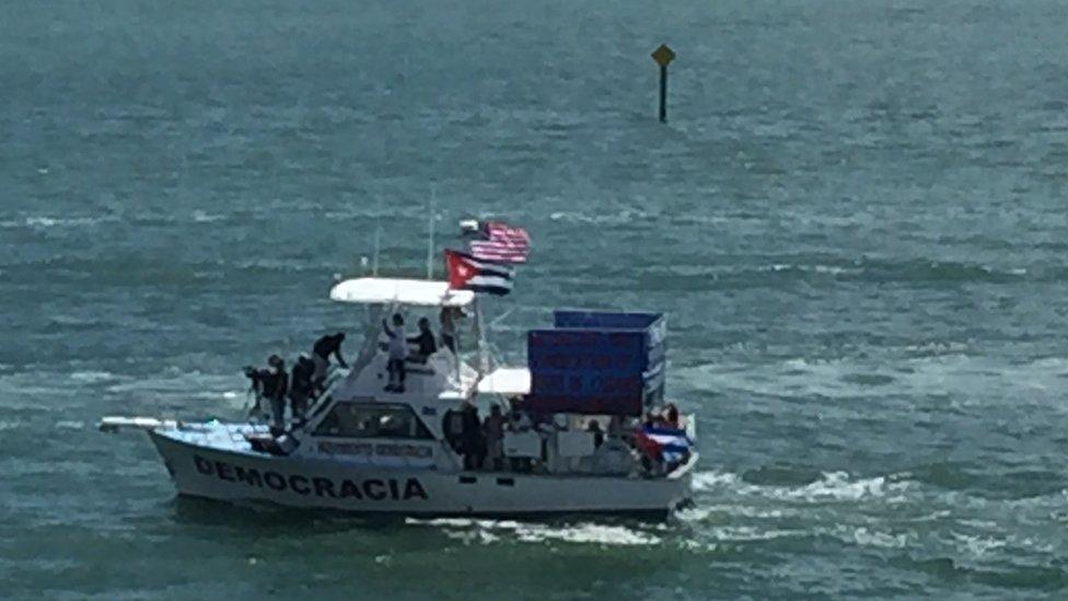 A ship with the word "democracy" in Spanish protests against a cruise ship heading for Havana