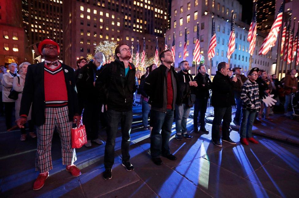 A crowd watches a news report at Rockefeller Center