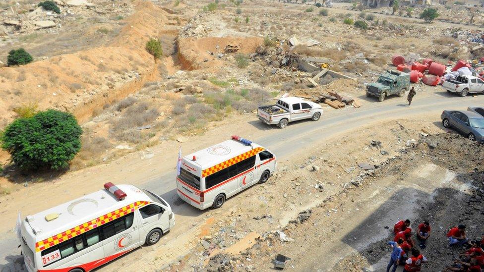 A Syrian Arab Red Crescent convoy waits at the entrance of the besieged Damascus suburb of Darayya.