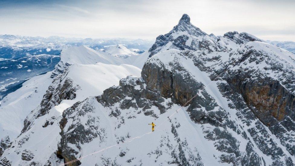 Mountains background with man walking tightrope