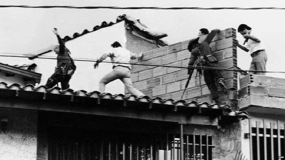 Colombian police and military forces storm the rooftop where drug lord Pablo Escobar was shot dead just moments earlier during an exchange of gunfire between security forces and Escobar and his bodyguard on 2 December 1993.