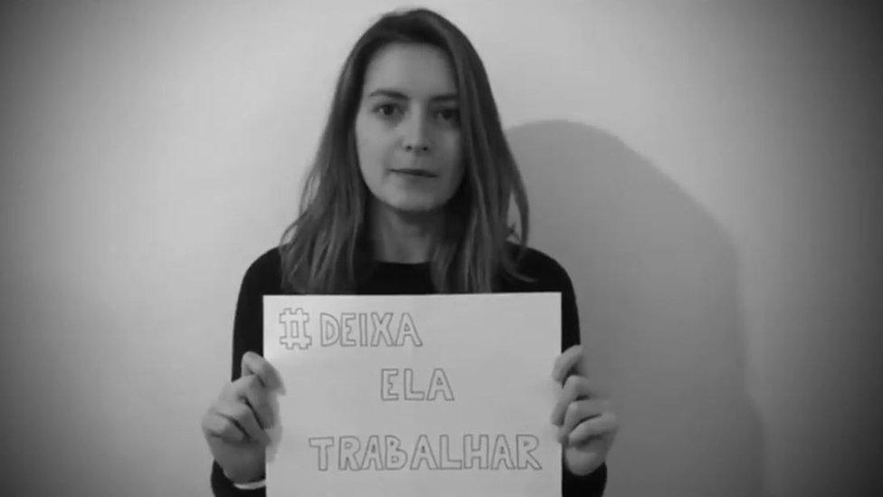 A female reporter holds up a sign saying "Let her work" in Brazil