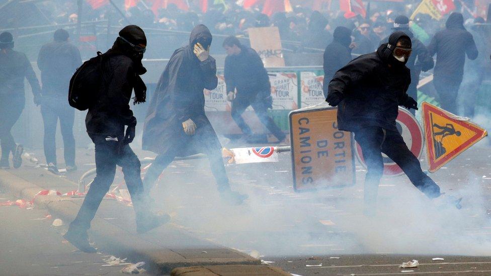 Tear gas floats around masked protesters during clashes with French CRS riot police at the May Day labour union rally in Paris, France 1 May 2018.