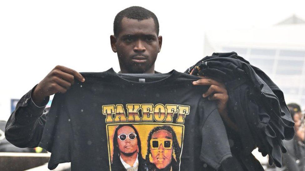 A fan holds up a shirt honouring Takeoff as he stands in line at the late rapper's memorial service