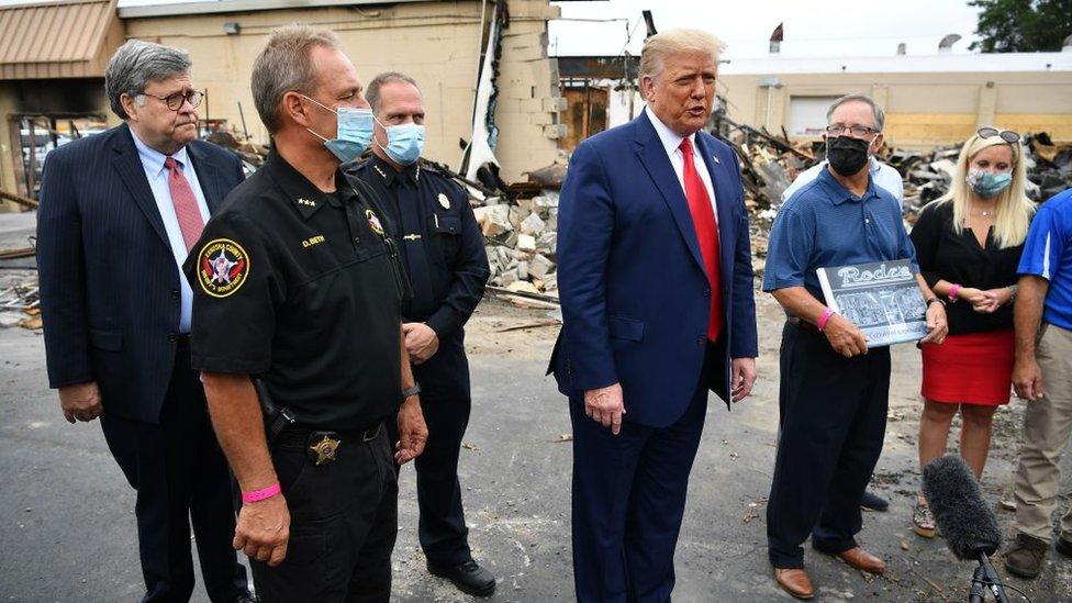 Mr Trump posed in front of a burned down camera shop with a man he wrongly claimed to be the business owner