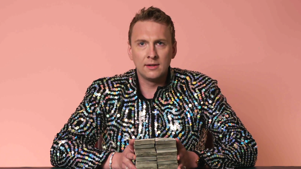 Joe Lycett holds onto £10,000 in cash