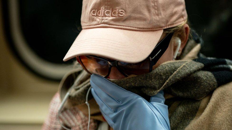 A woman wearing a protective mask sits in a subway car at Grand Central Terminal on March 12, 2020 in New York City