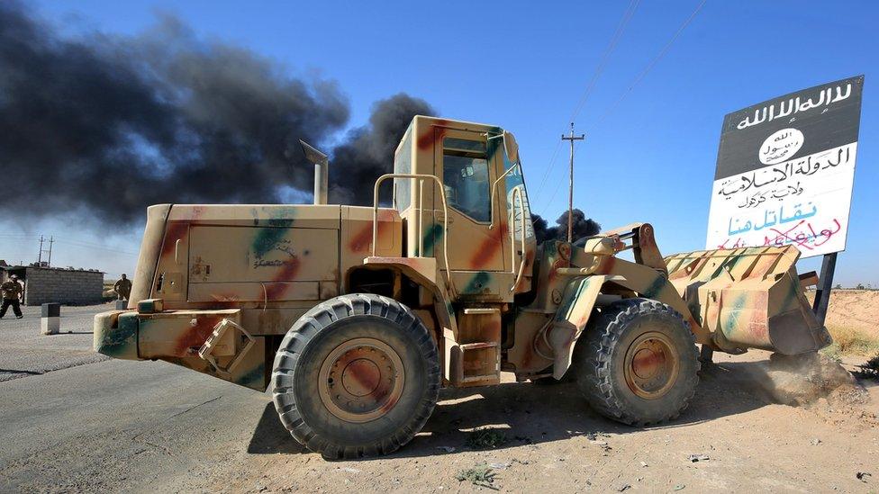 A bulldozer pushes over an Islamic State group sign as Iraqi forces move towards Hawija on 4 October 2017