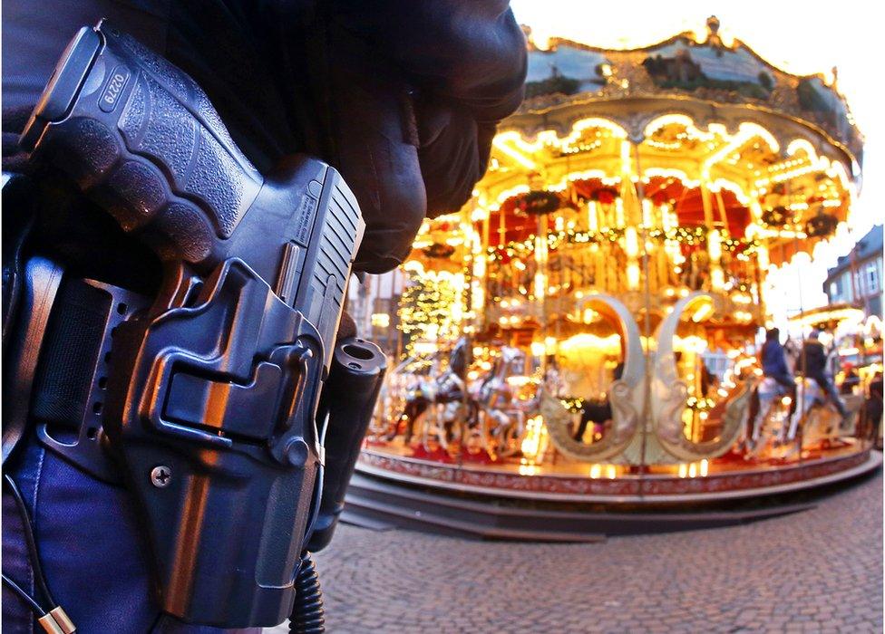 A German police officer stands next to a merry-go-round in the Christmas market in Frankfurt, Germany, 20 December