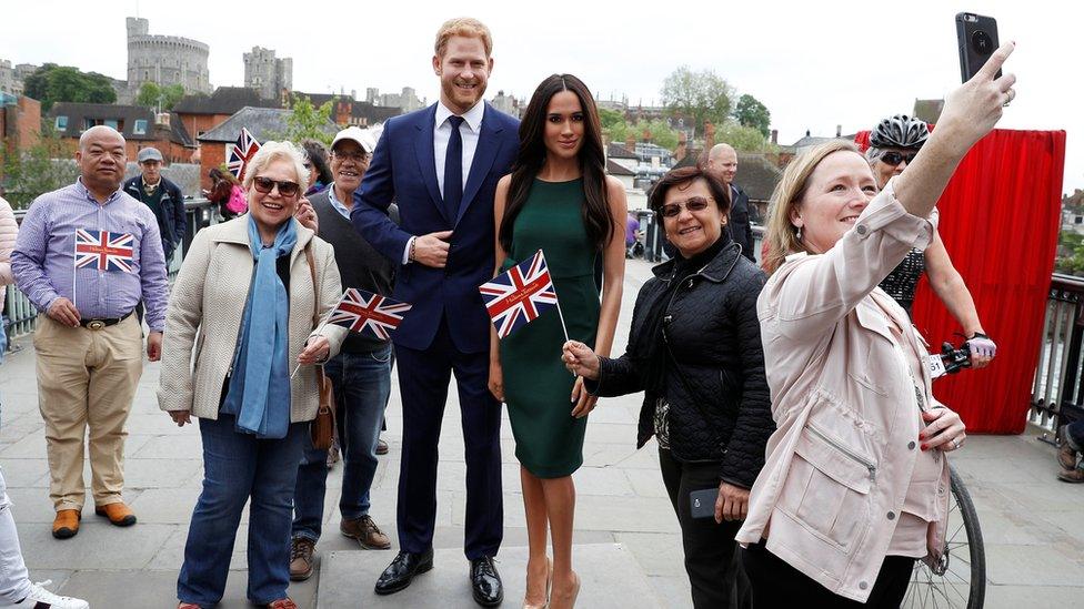 People pose for pictures and selfies with models of Britain's Prince Harry and Meghan Markle ahead of their wedding, in Windsor