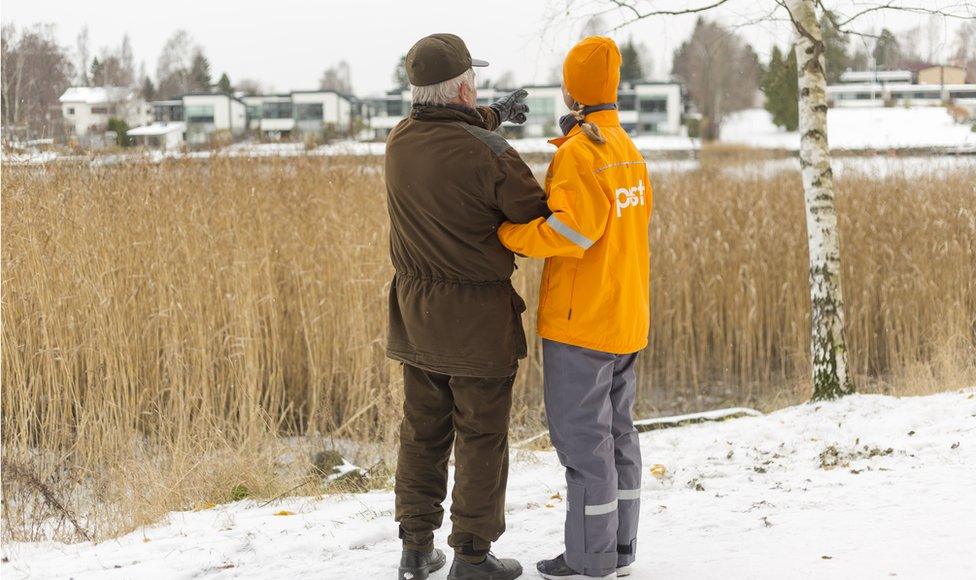 A promotional photo from Posti showing a female worker linking arms with an elderly man outside in the snow