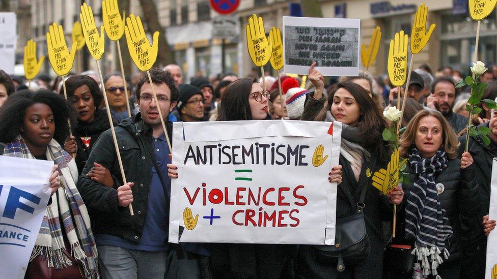 Demonstrators hold signs against anti-Semitism during a silent march in Paris on March 28, 2018, in memory of Mireille Knoll