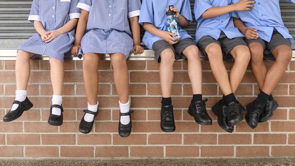 two-girls-and-three-boys-sitting-on-a-wall-with-different-kinds-of-school-shoes