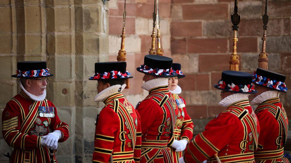 Anëtarët e Gardës duke pritur mbërritjen e Çarlsit dhe Mbretëreshës Kamila. Ata kanë veshur uniforma dalluese të stilit Tudor, të kuqe të ndezur me zbukurime kadifeje blu dhe të arta. Ata kanë veshur gjithashtu një kapelë të zezë në stilin Tudor.