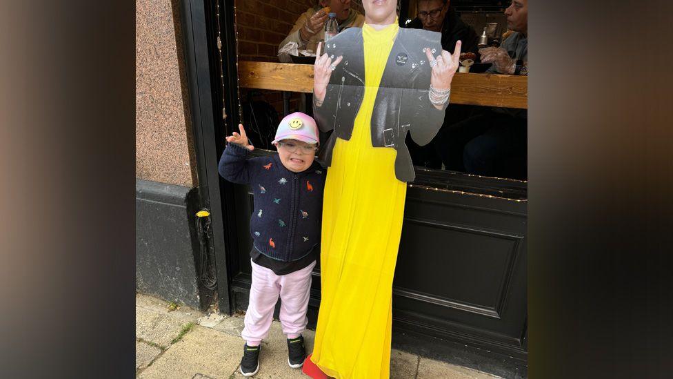 Jesse standing next to a cardboard cutout image of Pink