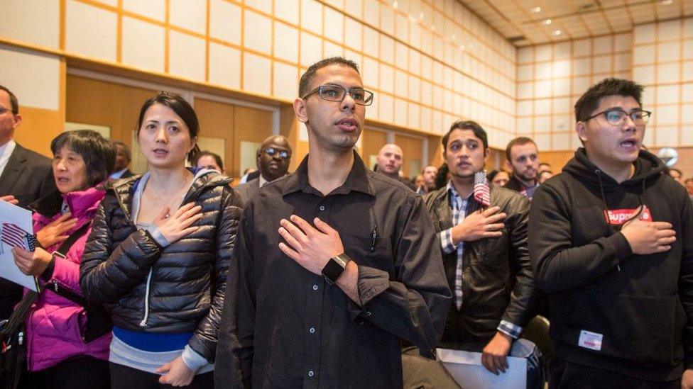 : A group of over 200 immigrants during the singing of the National Anthem at a Naturalization Oath Ceremony at the John F. Kennedy Presidential Library and Museum on February 8, 2017