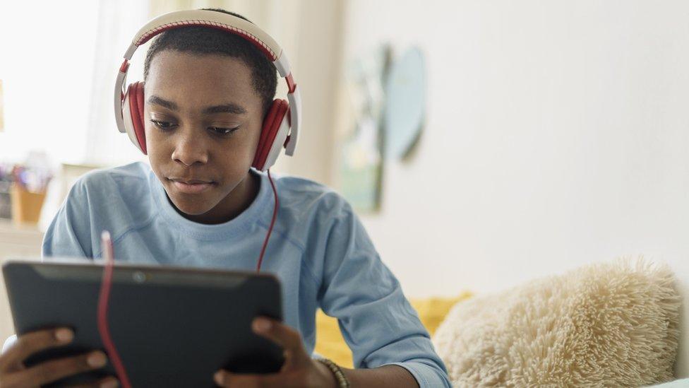 Boy listening to music through headphones.