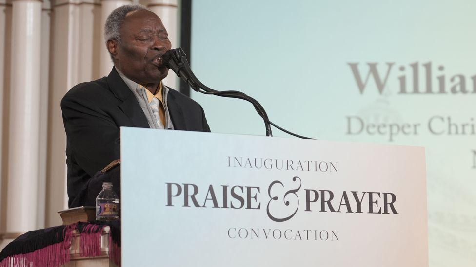 William Kumuyi standing at a pulpit behind a sign that says "Inauguration Praise and Prayer Convocation".