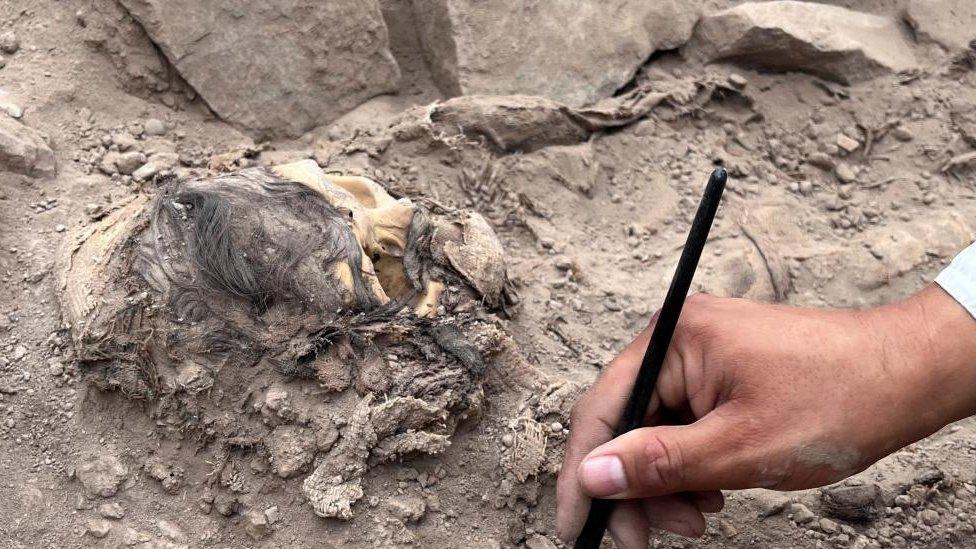 An archaeologist works at the excavation site of a pre-Hispanic burial next to a mummy believed to be from the Manchay culture, which developed in the valleys of Lima between 1,500 and 1,000 BCE, in Lima, Peru, June 14, 2023.