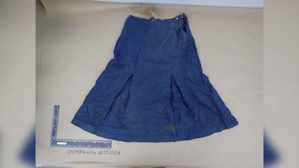 A blue skirt spread out on a piece of grey card. A ruler is in the corner for scale. A date is written beneath the ruler.