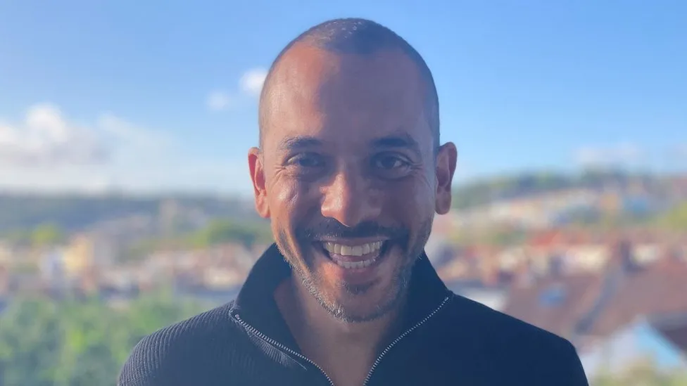 Head and shoulders image of Roy Kareem in a black jacket, smiling