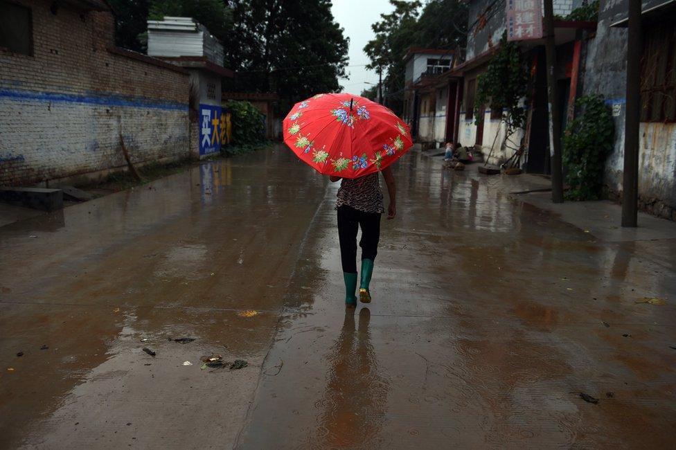 A woman walks down the main street in Weijian village, in China's Henan province on 29 July 2014