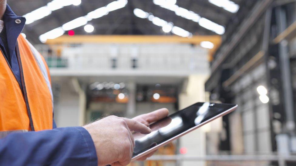 Steelworker using digital tablet in engineering factory, close up - stock photo