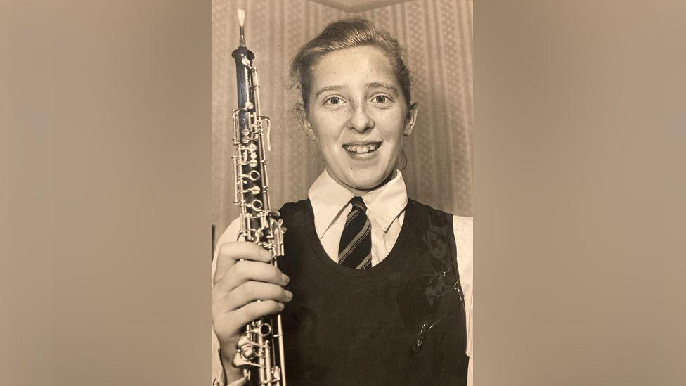 Young girl wearing school uniform holding oboe