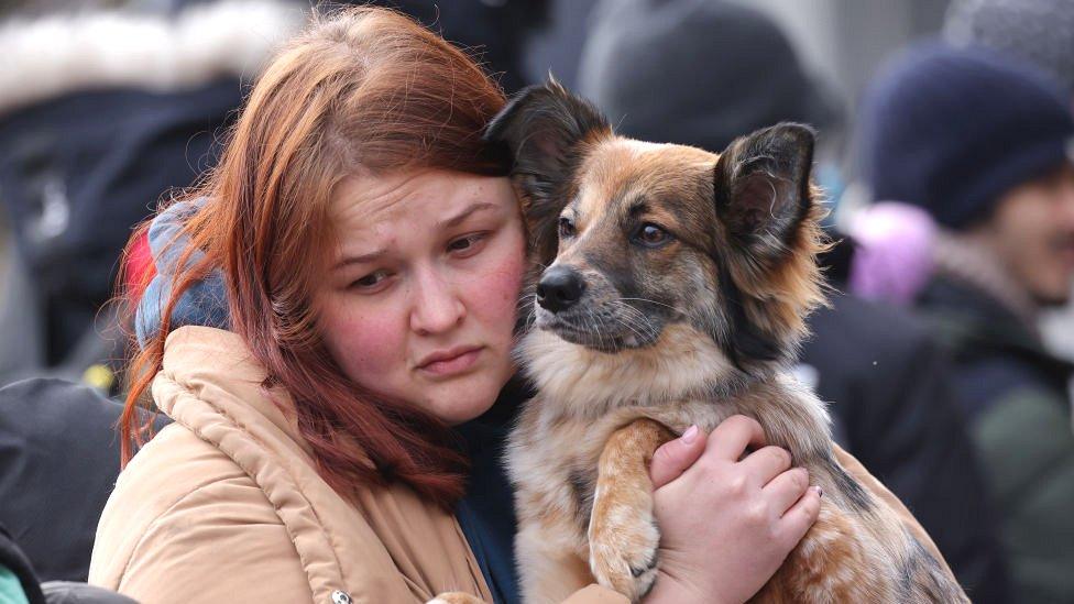 A young woman arriving from Ukraine clutches her dog as they wait to cross into Poland