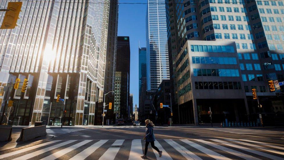 A woman crosses the street during morning commuting hours in the Financial District as Toronto copes with a shutdown due to the Coronavirus, on April 1, 2020 in Toronto, Canada