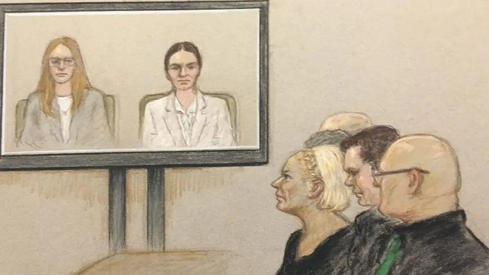 Drawing of people watching a video monitor in court. The screen is showing two seated women - one has long light brown hair and is wearing a light-coloured jacket,the other (Anne Sacoolas) has dark hair tied back. There are five people watching the screen.