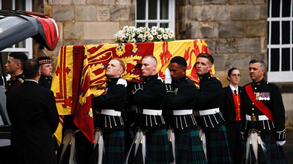 Pallbearers carrying the coffin of Queen Elizabeth II, draped with the Royal Standard of Scotland, as it arrives at Holyroodhouse