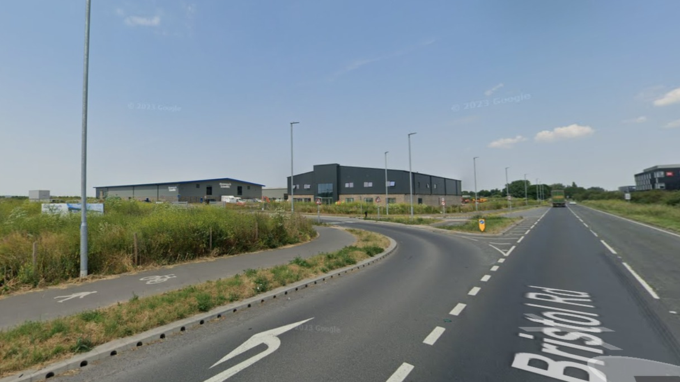 Roads adjacent to the planning site, with some green shrubbery to the left and a lamp post