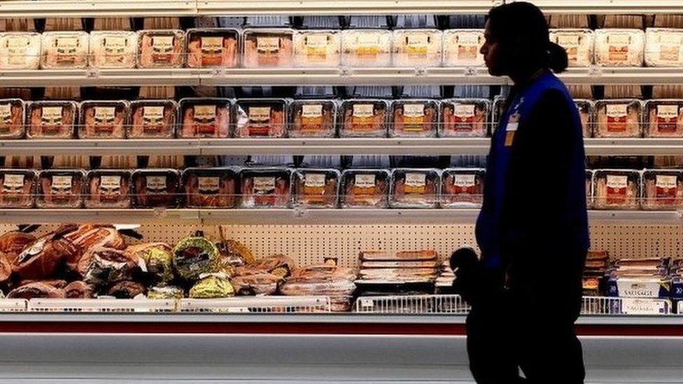 Woman walks past chicken in a US shop