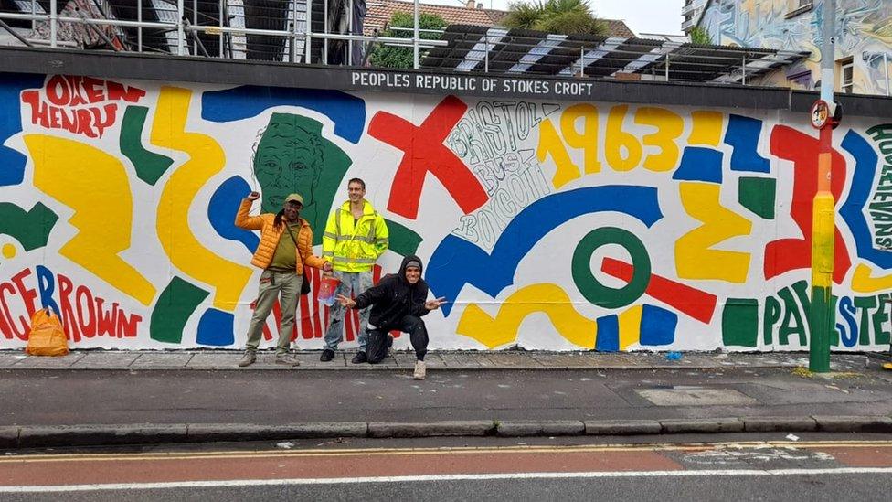 Three men standing in front of the mural