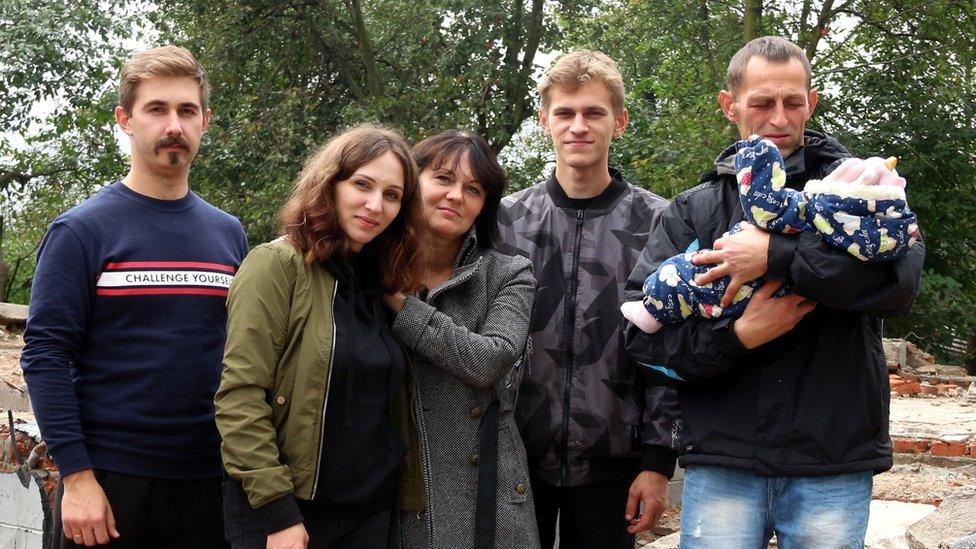 Pylypenko family in front of their destroyed house