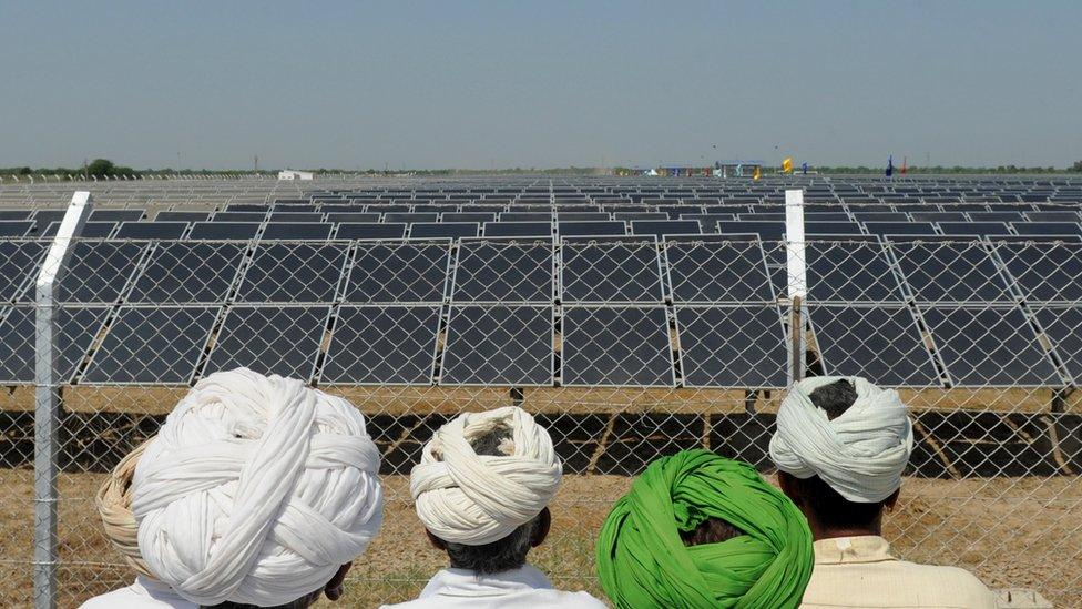 Indian farmers look at a solar farm