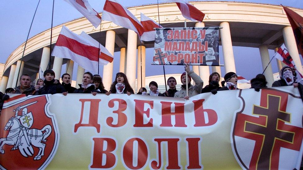 An opposition march in Minsk with protestors holding a banner featuring the Pahonia