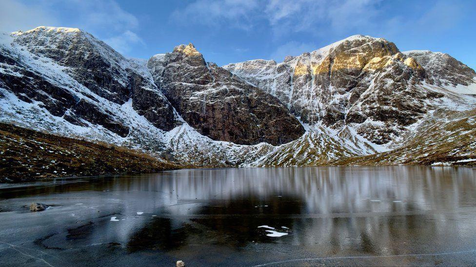 Snowy mountains surrounding icy water.