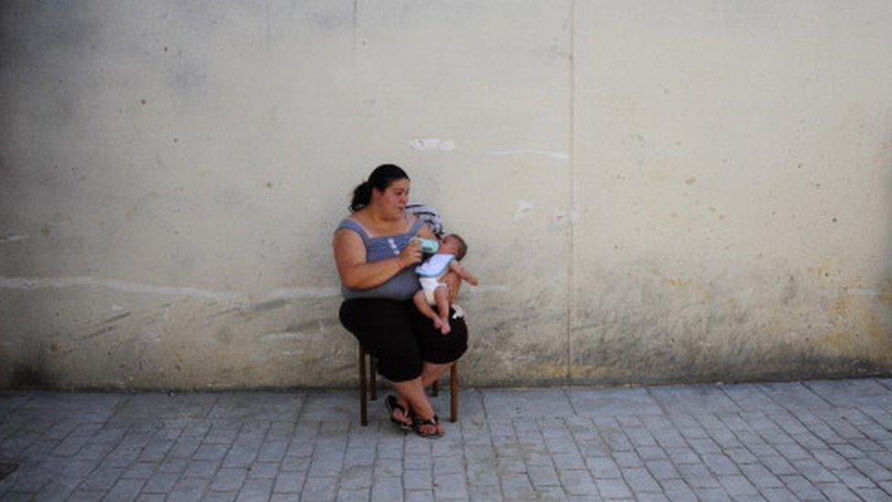 Woman feeds her baby at an abandoned building project on the outskirts of Bollullos Del Condado, Spain (13 June 2013)