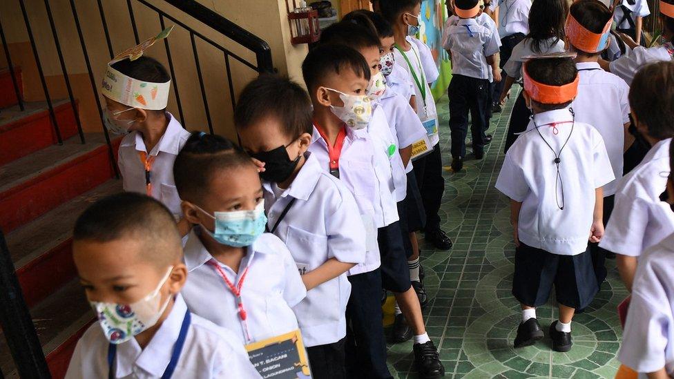 Teachers watch their students walk along a corridor after a short break at the start of classes at a school in Quezon City,