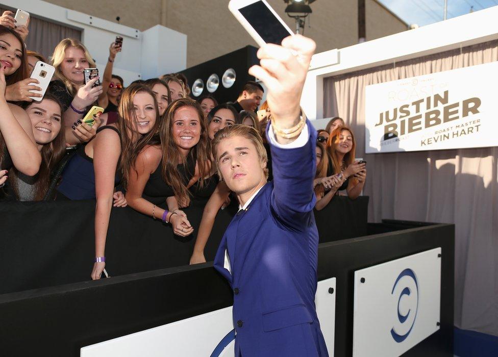 Justin Bieber taking a selfie with fans