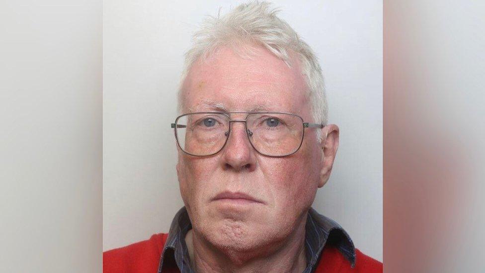 Man with medium-length white hair and glasses