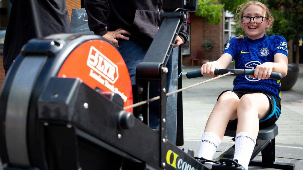 A girl wearing a Chelsea shirt on a rowing machine