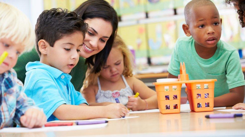 Teacher helping children to draw