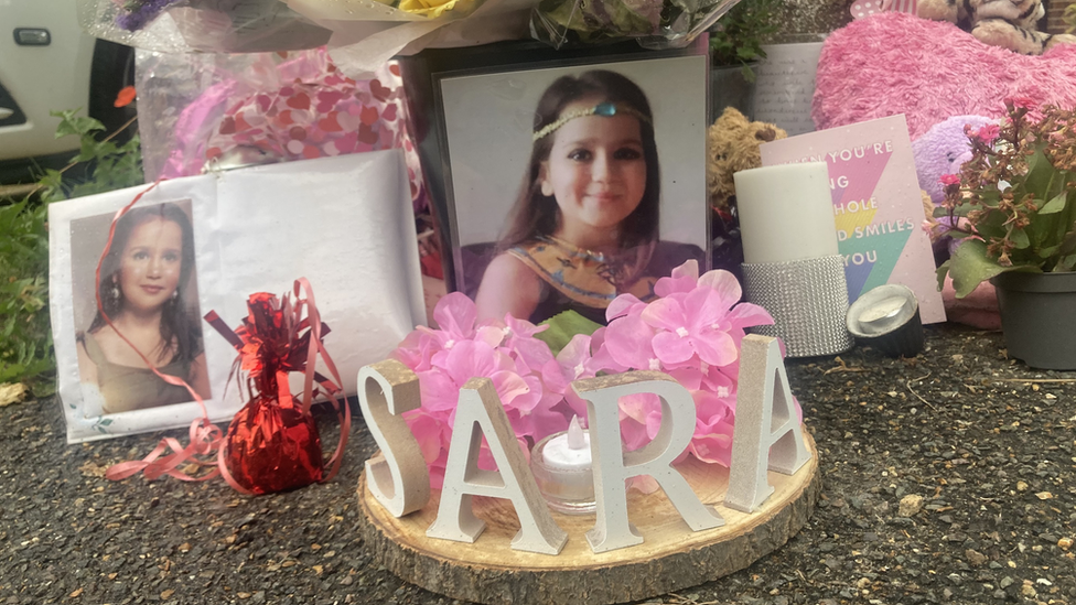 Flowers and pictures of Sarah outside the family home in Woking, Surrey