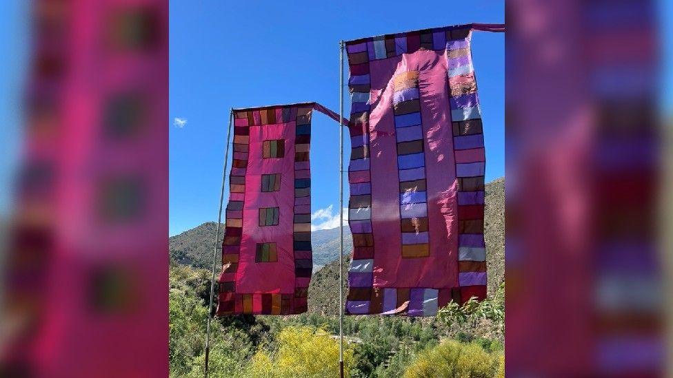 Long narrow flags made up of maroon, blue, red, green and tan rectangles