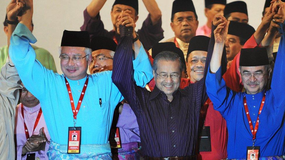 Mahathir (C) and Najib (L) stand at an UMNO annual general assembly meeting in 2009