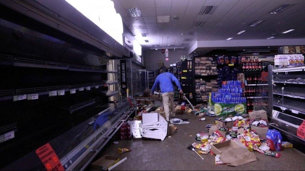 A self-armed local looks for looters inside a supermarket following protests that have widened into looting, in Durban, South Africa July 13, 2021, in this screen grab taken from a video